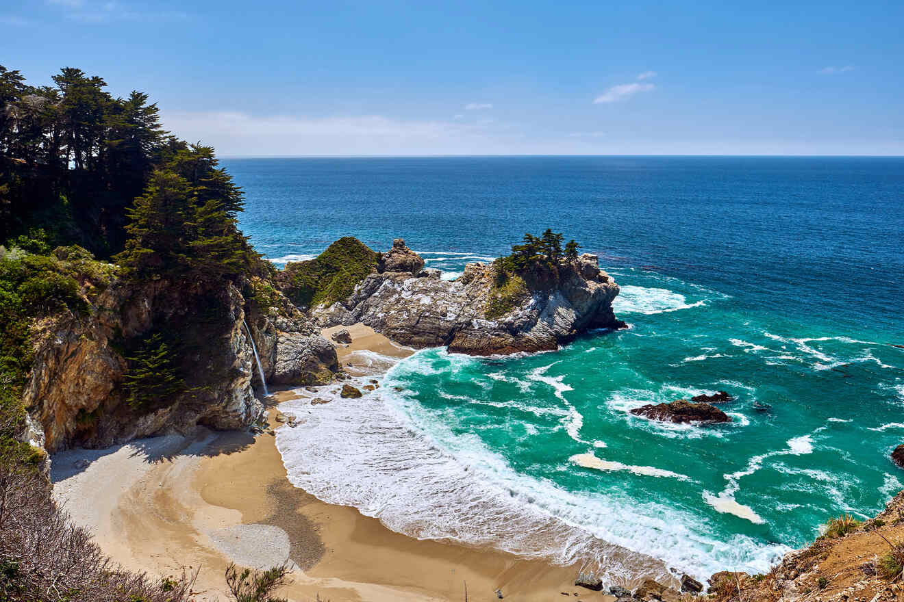 the ocean next to a beach with a cliff and rocks